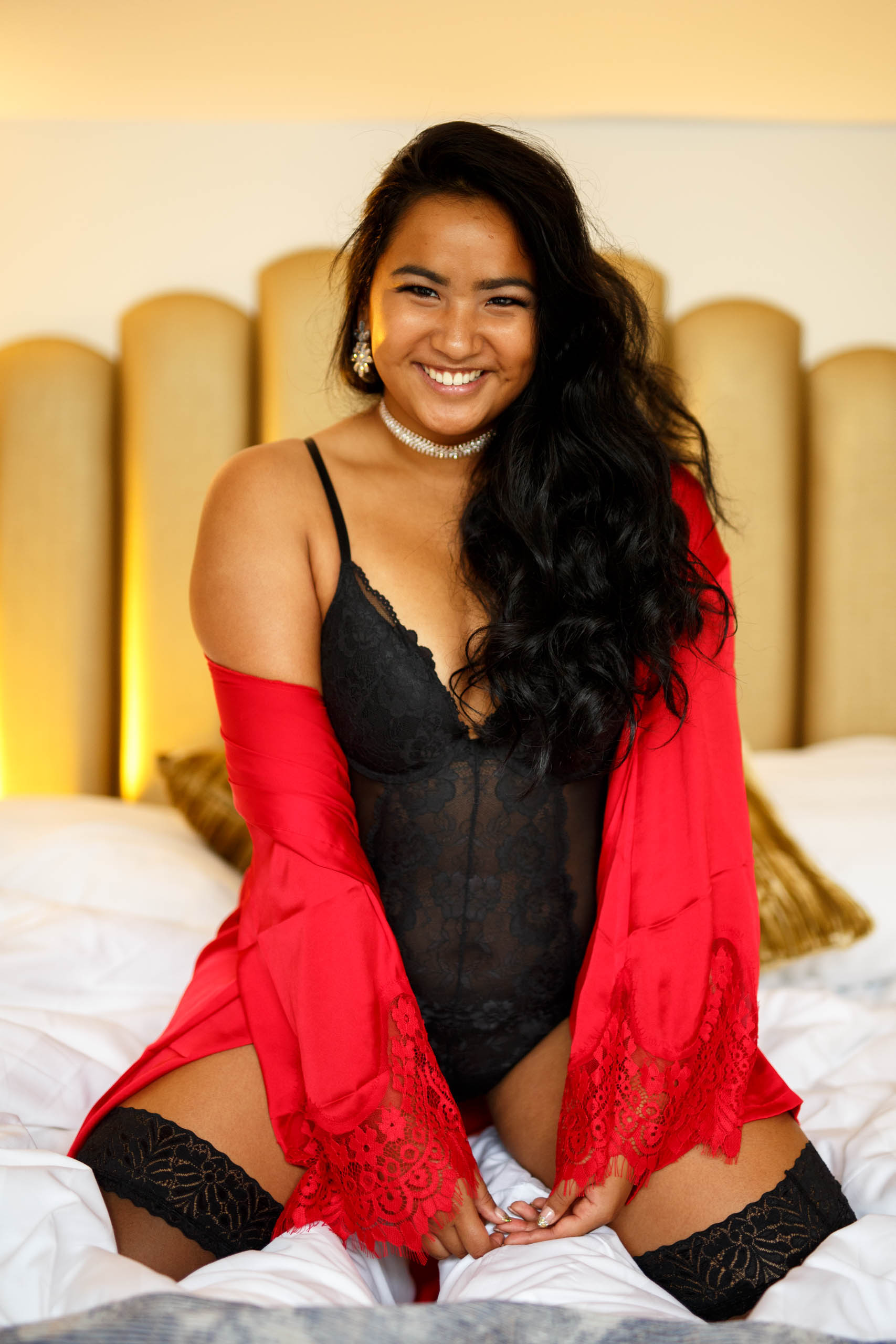 A woman in a red robe and stockings participating in a boudoir photo shoot, showing off the allure and benefits (advantages) of such an intimate setting.