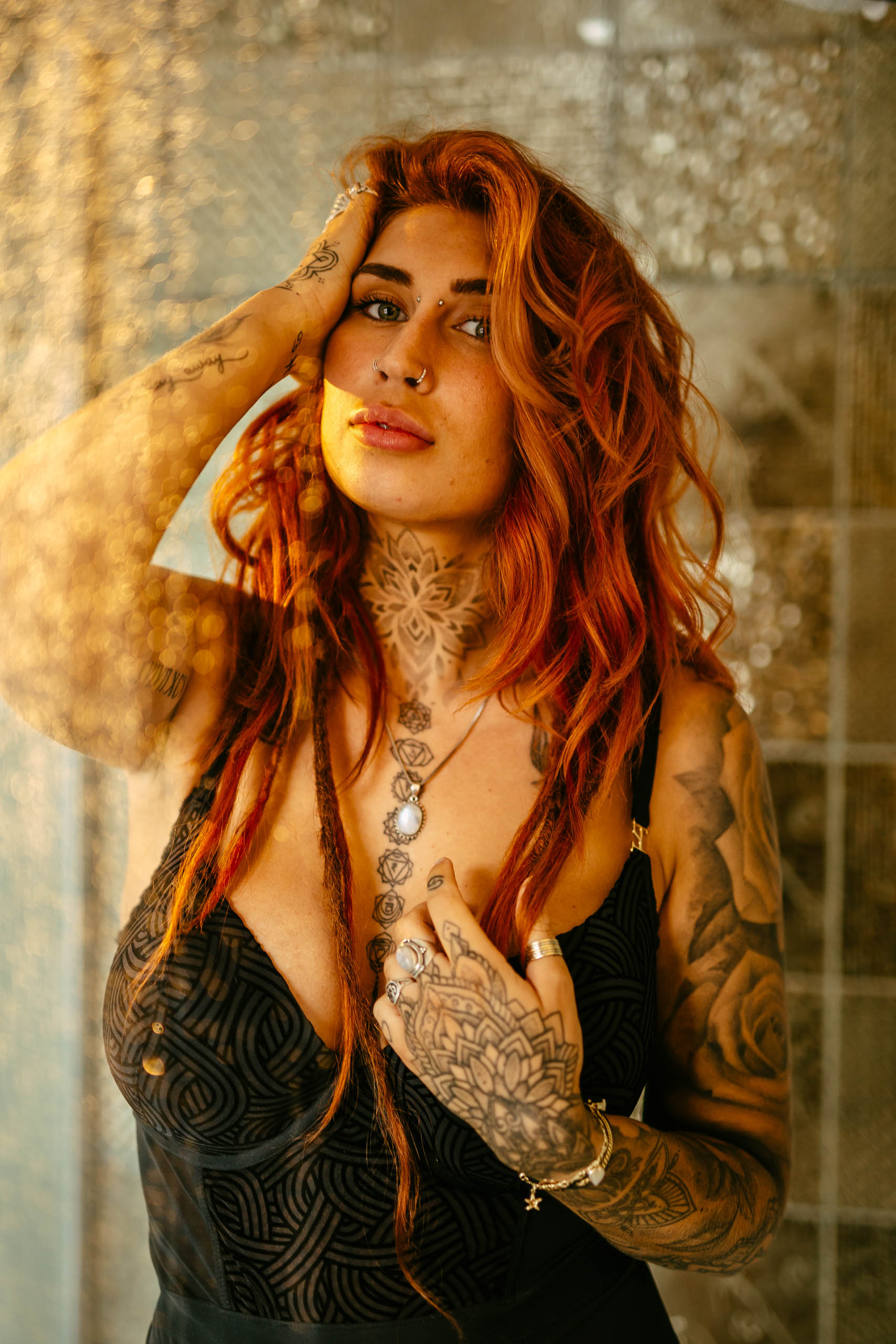 Een vrouw met rood haar en tatoeages poserend in een badkamer.