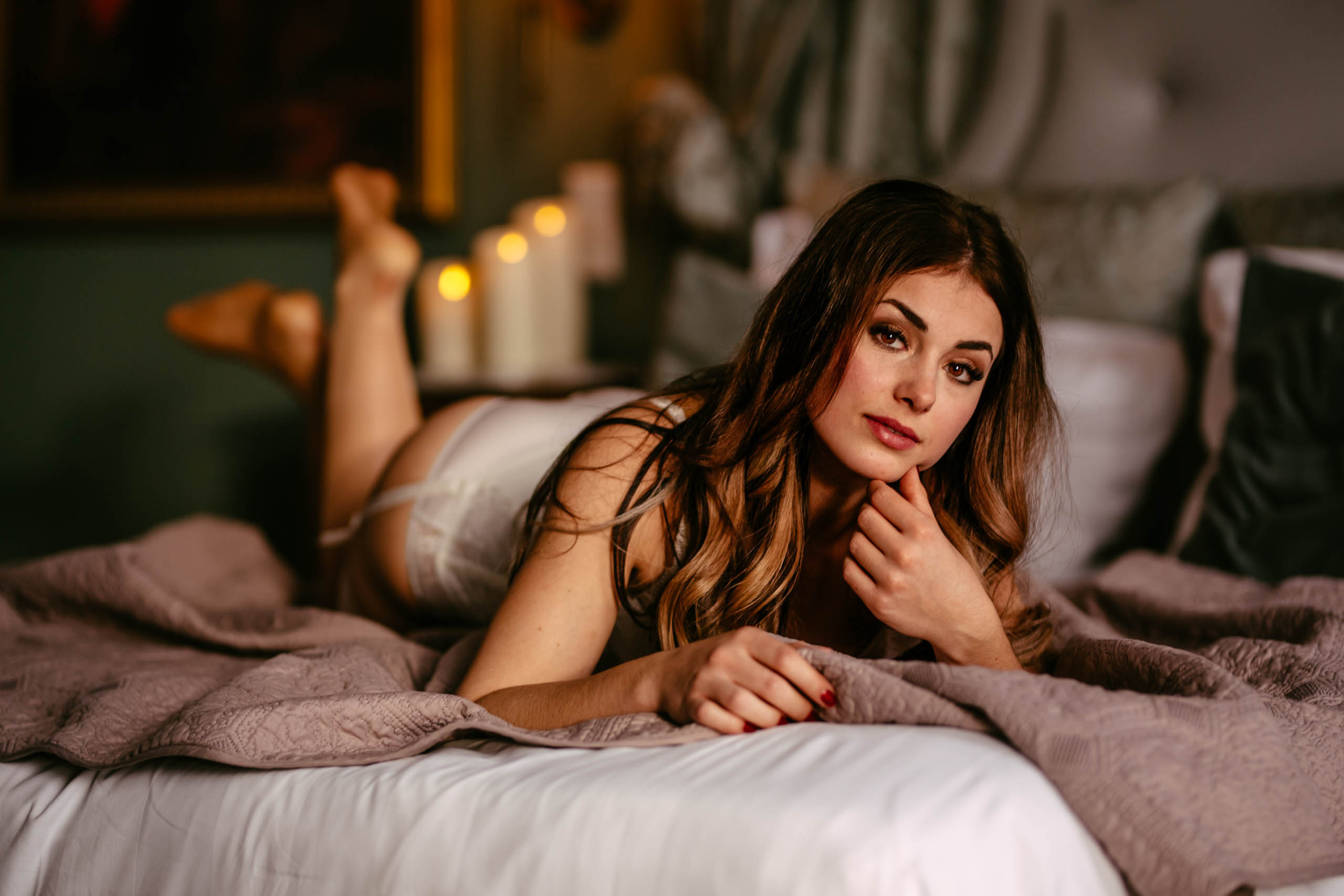 Een prachtig model poseert sensueel op een bed versierd met kaarsen tijdens een boudoirshoot in Delft.