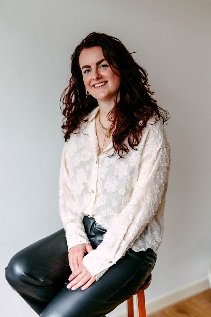 A woman in leather trousers sitting on a stool.