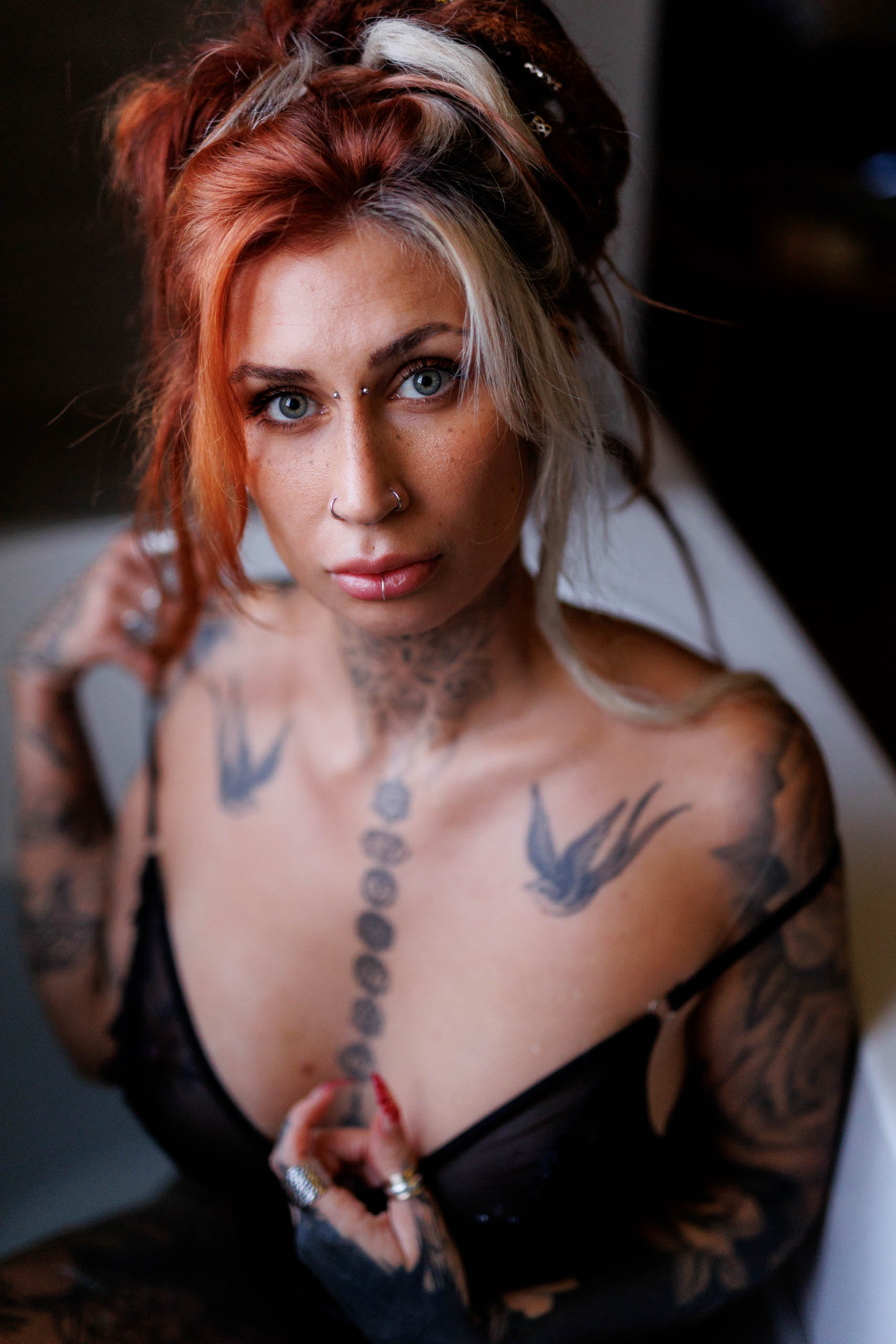 A glamorous woman with tattoos poses in a bathtub during a photo shoot.