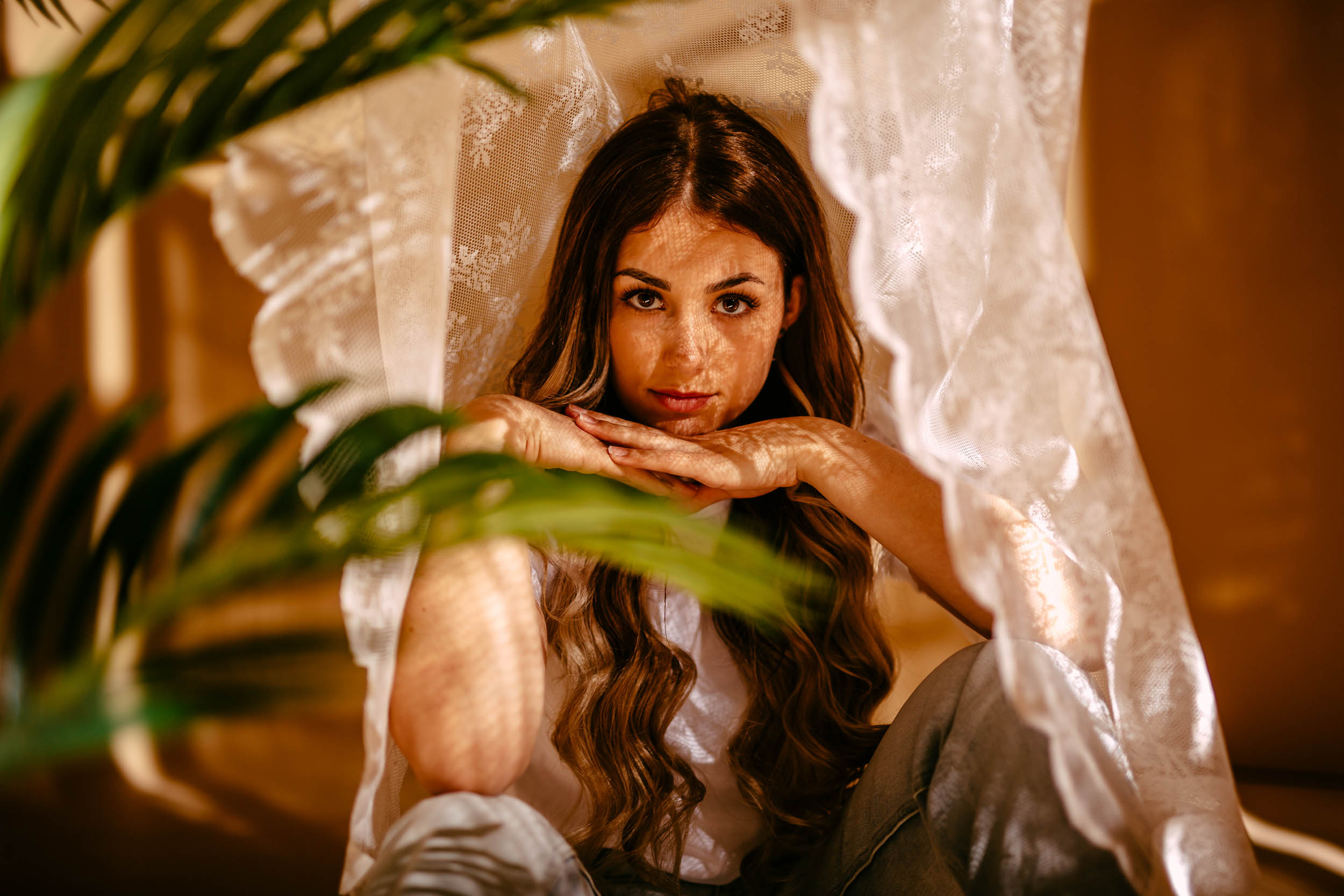 A woman sits under a curtain while making her model portfolio.