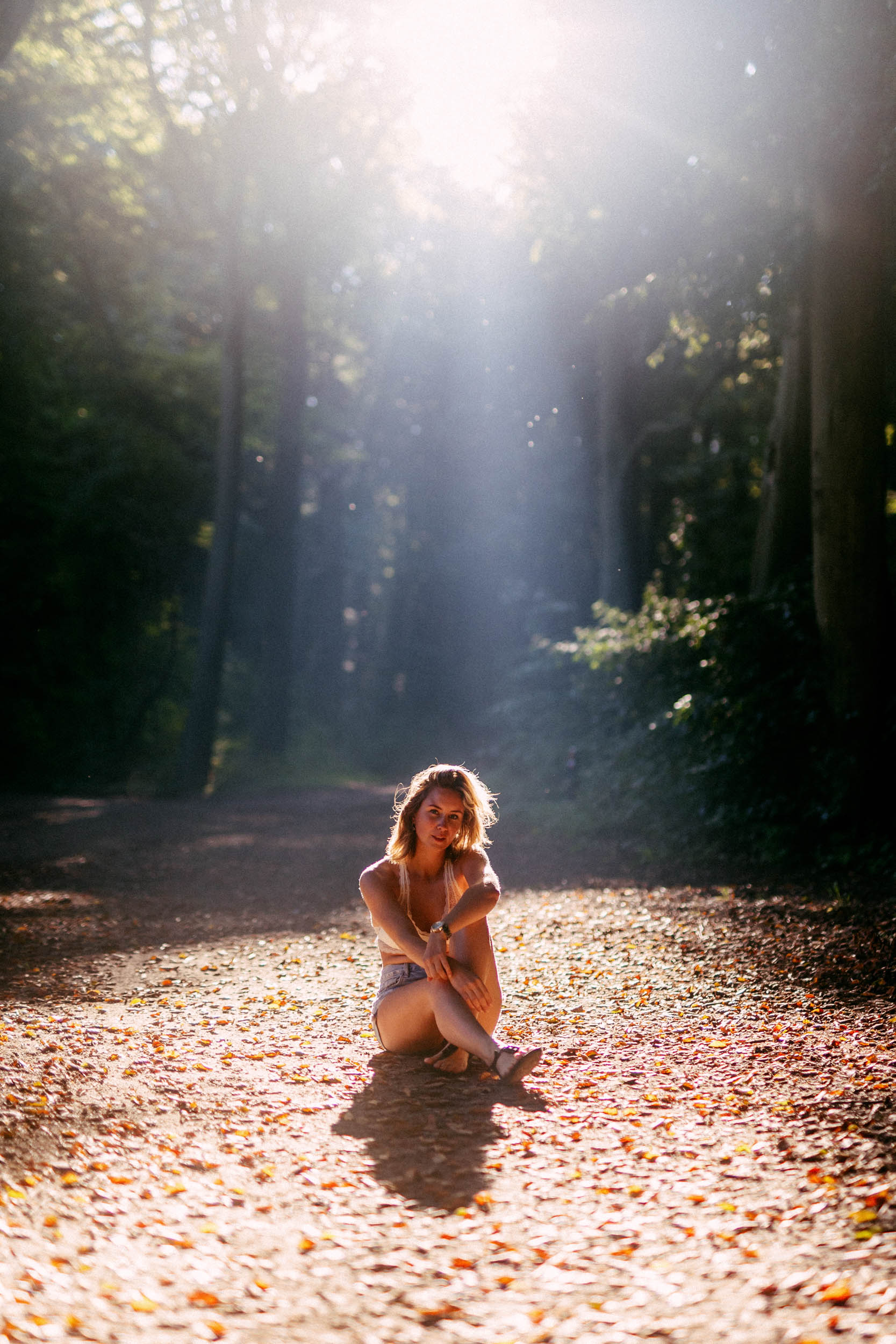 A woman sitting on the ground in a forest, captured in a beach photo.