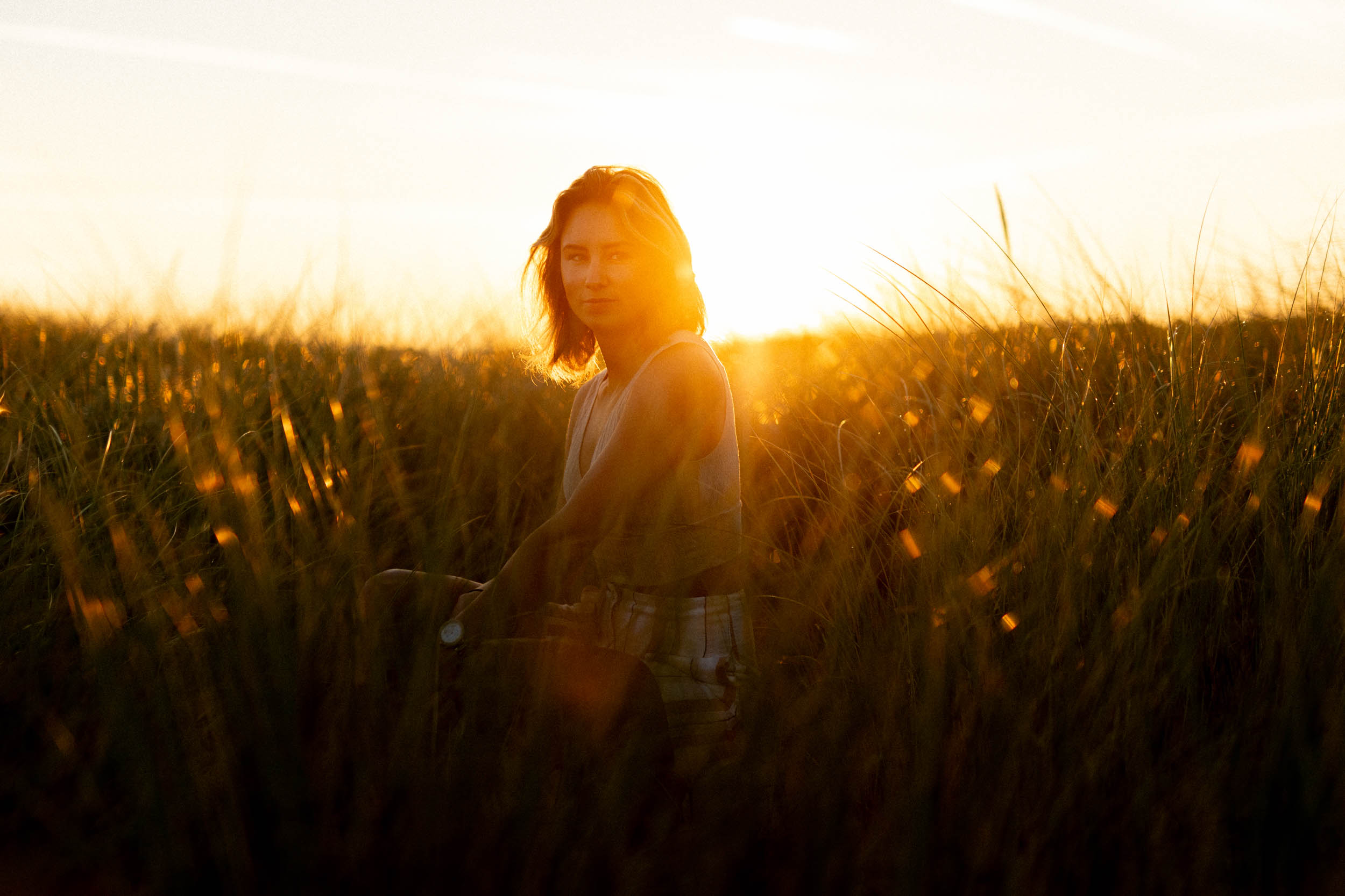A woman standing in a field, captured in a beautiful sunset photo.