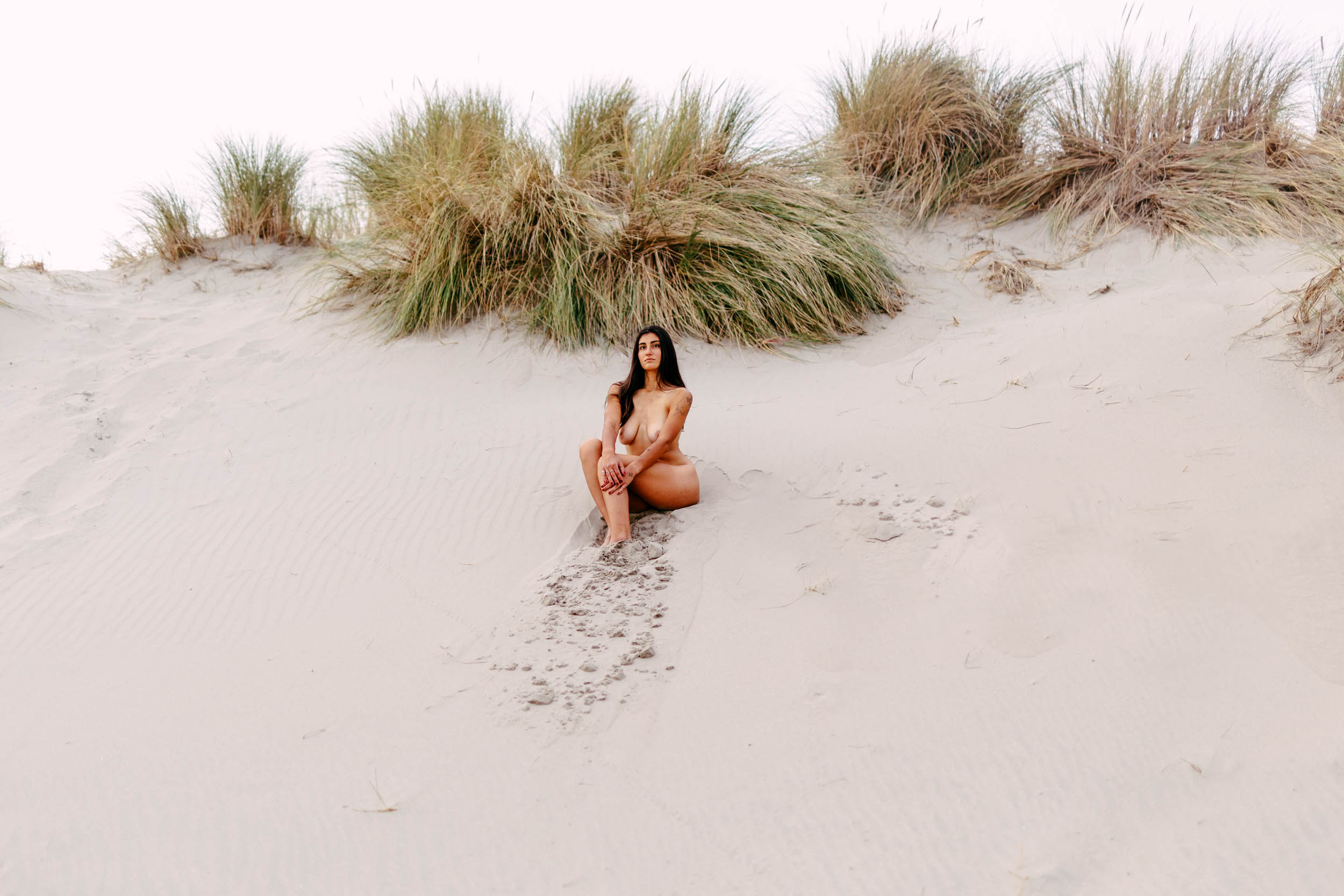 A woman poses for a beach photo shoot on the beach.