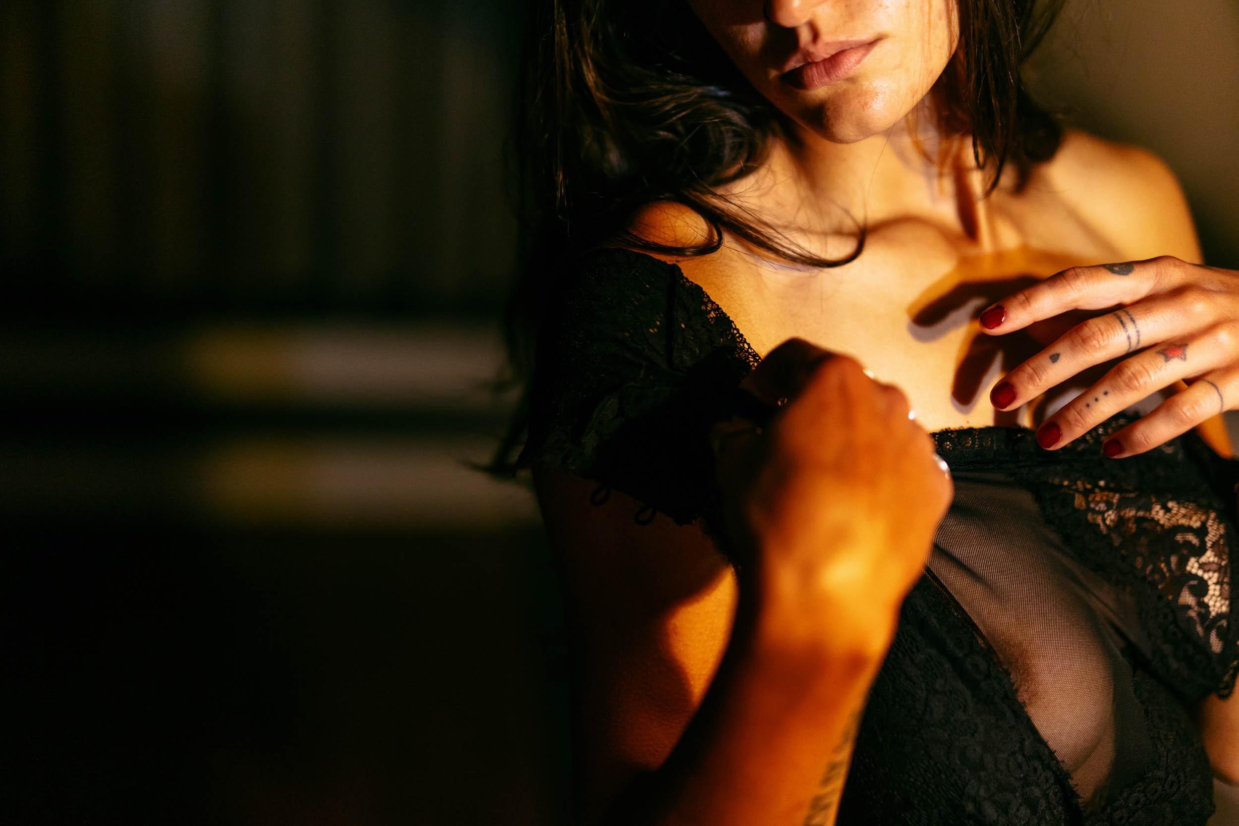 A woman in black lingerie poses during a photo shoot on a dark beach.