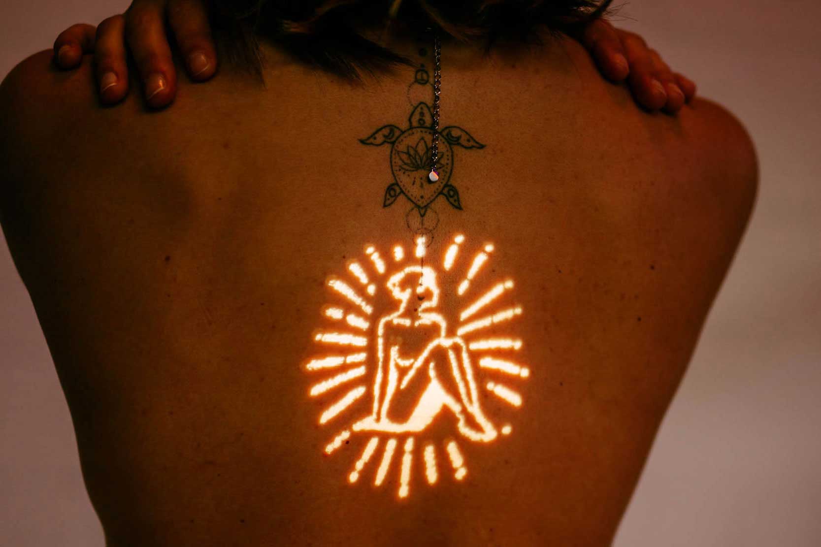 De rug van een vrouw versierd met een stralende tatoeage met krachtige zelfliefde-citaten.
