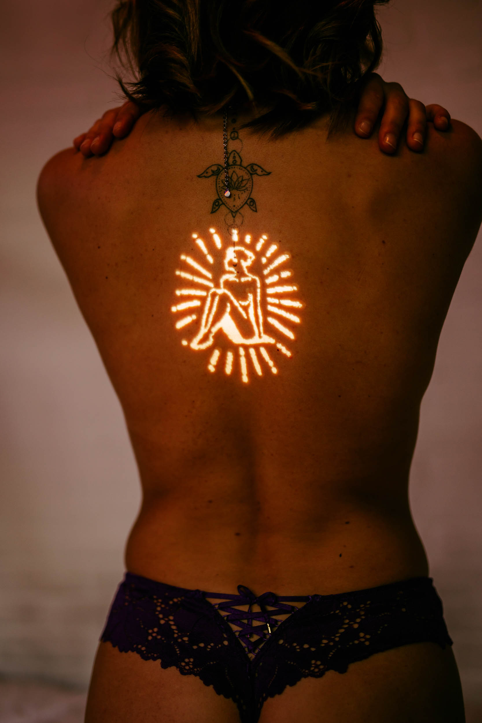 A woman with a sun tattoo on her back.