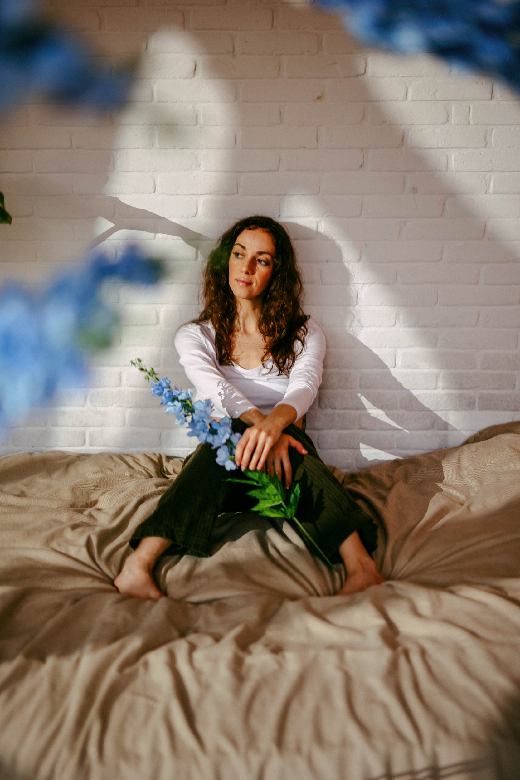 Een vrouw zittend op een bed met blauwe bloemen.
