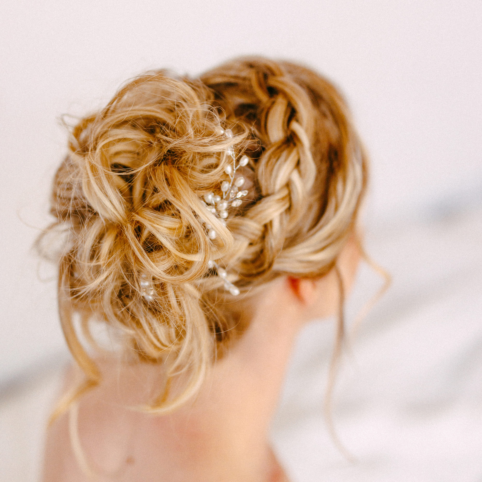 Achterkant van een vrouw met blond haar, gestyled in een ingewikkeld opgestoken kapsel met vlechten en kleine decoratieve parels, perfect voor elegante fotoshoots of Boudoir Recensies. Achterkant van een vrouw met blond haar, gestyled in een ingewikkeld opgestoken kapsel met vlechten en kleine decoratieve parels, perfect voor elegante fotoshoots of Boudoir Recensies.